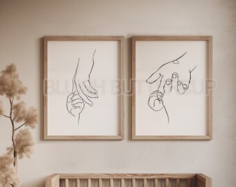 Puede incluir: Dos dibujos en blanco y negro enmarcados de manos que se toman de la mano. Los dibujos son de estilo minimalista y están colgados en una pared beige claro sobre una cuna de madera.