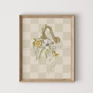 Pu&ograve; includere: Una lampada in metallo dorato con un design floreale. La lampada &egrave; circondata da fiori bianchi e gialli e foglie verdi. La lampada &egrave; su uno sfondo a scacchi beige e bianco.
