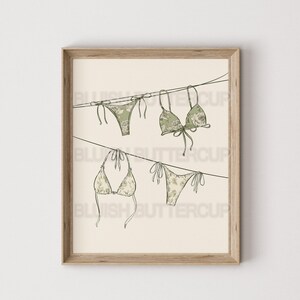 May include: A digital illustration of three green and white floral patterned bikinis hanging on a clothesline. The bikinis are drawn in a simple line style.