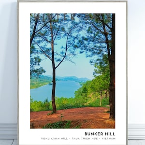 May include: Framed print of Bunker Hill in Vietnam. The landscape features a serene blue lake surrounded by green trees and hills. The foreground shows a reddish-brown path. The text "BUNKER HILL" and location details are at the bottom.