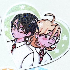 May include: A sticker featuring a cartoon illustration of two people with short hair. The person on the left is wearing glasses and a red tie. The person on the right is wearing a red tie and has a blush on their cheeks. The background is green with white flowers.