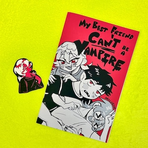 May include: A red comic book with the text "My Best Friend Can't Be A Vampire" and a matching sticker. The comic features a black and white illustration of three characters with red eyes. The background is neon yellow.