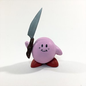 以下が含まれることがあります： 白い背景に立っている、笑顔のピンクのキャラクター。キャラクターは、茶色の柄の銀色のナイフを持っている。キャラクターは赤い靴を履いている。