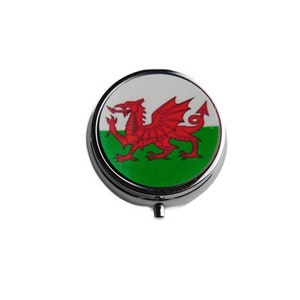 May include: A round, silver pill box with a white and green Welsh flag design featuring a red dragon.