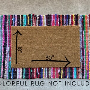 May include: A brown coir doormat with a colorful braided rug border. The doormat measures 30 inches by 18 inches. "COLORFUL RUG NOT INCLUDED" is printed below the doormat.