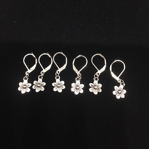 May include: Six silver flower charm earring hooks. Each hook features a small, silver flower charm.