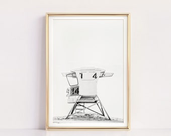 May include: Black and white photograph of a lifeguard stand on a beach. The stand has the number "14" on it.