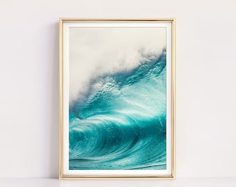 May include: A photograph of a large, turquoise wave crashing in the ocean. The wave is backlit by the sun, creating a bright, ethereal glow. The image is framed in a gold frame.