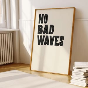 May include: A framed print with the text "NO BAD WAVES" in black bold letters on a white background. The frame is made of wood and has a light brown finish.