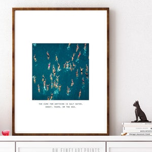 May include: A framed print with a photograph of a group of people swimming in the ocean. The text below the image reads "The cure for anything is salt water, sweat, tears, or the sea."