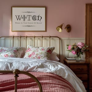 Puede incluir: Un dormitorio con una cama de lat&oacute;n, cojines florales y un edred&oacute;n rosa. Un cuadro en la pared dice "WITCH: Woman In Total Control Of Herself." Una l&aacute;mpara de pared dorada y un jarr&oacute;n de flores completan el ambiente acogedor.