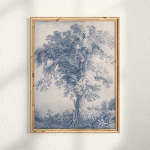 May include: A framed print featuring a detailed blue and white illustration of a large tree with sprawling branches and foliage. The artwork, reminiscent of a vintage etching, includes a landscape with a road and small buildings. The frame is a light wood color.