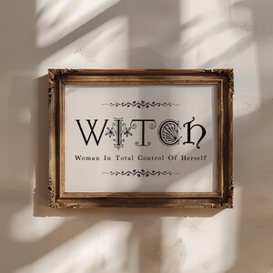 Puede incluir: Un cuadro enmarcado con la palabra "WITCH" en letras negras ornamentadas y la frase "Woman In Total Control Of Herself" debajo. El marco es de madera oscura y ornamentada con tallas decorativas.