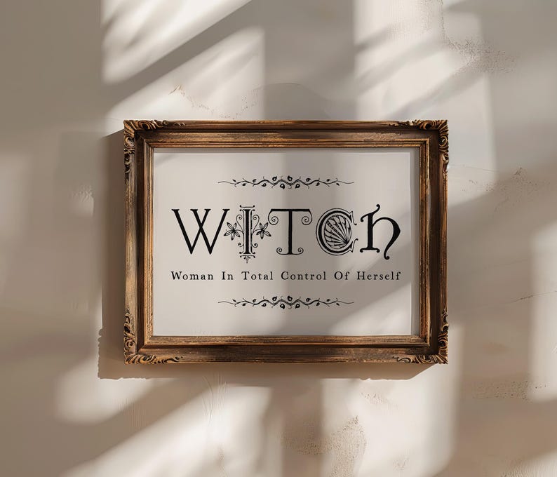 Puede incluir: Un cuadro enmarcado con la palabra "WITCH" en letras negras ornamentadas y la frase "Woman In Total Control Of Herself" debajo. El marco es de madera oscura y ornamentada con tallas decorativas.
