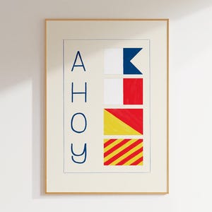 Puede incluir: Lámina artística enmarcada con la palabra "AHOY" en letras mayúsculas azules. La obra presenta banderas de señales en blanco, rojo, amarillo y azul, con un marco dorado. Las banderas están dispuestas verticalmente.