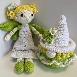 May include: Two handmade crochet dolls. One is a fairy with yellow hair, green wings, and a white dress. The other is a gnome with a white hat and a green and yellow dress. Both dolls are made with soft yarn.