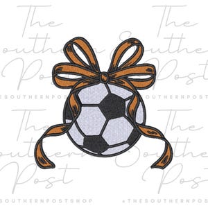 May include: A soccer ball design with a black and white pattern, adorned with a brown ribbon bow. The image has the text "The Southern Post" and "@THESOUTHERNPOSTSHOP" in the background.