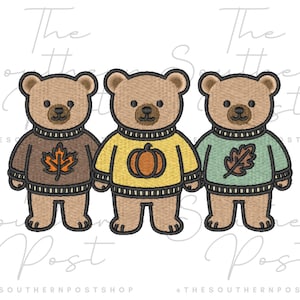 May include: Three embroidered teddy bears wearing jumpers with autumn designs. The jumpers are brown with a leaf, yellow with a pumpkin, and green with a leaf. The bears are standing side by side.