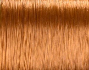 May include: Close-up of a spool of shiny, copper-colored thread.