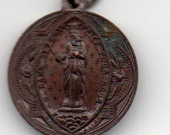May include: An oval-shaped, bronze-colored medal with a raised image of a saint holding a staff and a book. The medal has a decorative border with the words "Santa Rita" and "Ora Pro Nobis" inscribed around the edge.