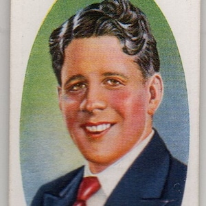 May include: A vintage trading card featuring a portrait of Rudy Vallee, a popular American singer and bandleader. The card is oval-shaped and has a green background. The text "Lambert & Butler's Cigarettes" is printed at the top of the card.