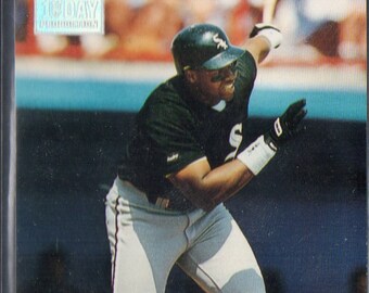 May include: A baseball card featuring Frank Thomas, a Major League Baseball player for the Chicago White Sox. The card is from the 1993 Topps Stadium Club series. The card shows Thomas in a batting stance, wearing a white uniform with a green and black jersey. The card has a gold border and a gold Topps Stadium Club logo.