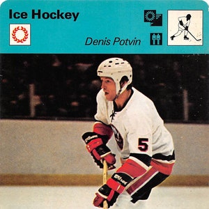 May include: A hockey player wearing a white jersey with a red and black stripe, black pants, and a white helmet with a black visor. The player is holding a wooden hockey stick and is skating on the ice. The player's jersey has the number "5" on the front. The image is from a hockey card with the text "Ice Hockey" and "Denis Potvin" on the top.