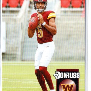 May include: A football trading card showing Jayden Daniels in a burgundy and gold uniform, holding a football. The card features the Donruss logo and the Washington Commanders' logo. The number 5 is visible on the jersey.