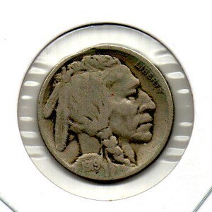 May include: A silver Buffalo nickel coin, featuring a Native American profile on the obverse and a buffalo on the reverse. The coin is encased in a clear, circular holder. The year 1919 is visible on the coin.