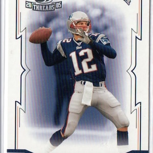 May include: A sports trading card featuring Tom Brady in a navy blue and silver football uniform with the number 12, throwing a brown football. The card includes the text Throwback Threads 05, Tom Brady, and Quarterback with a Patriots logo.