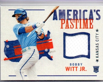May include: Baseball trading card with a player in a blue uniform swinging a bat. The card features the text "AMERICA'S PASTIME" and "BOBBY WITT JR.". The background has a blue and red design.