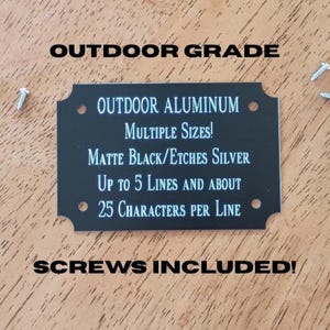 May include: A black outdoor aluminum sign with white text, including the words "Outdoor Grade" and "Screws Included!" The sign has rounded corners and is accompanied by several screws.
