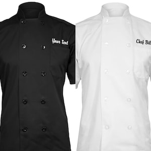 May include: Two chef jackets, one black and one white, with short sleeves and a double-breasted button closure. The black jacket has the text "Your Text" embroidered on the left chest, while the white jacket has the text "Chef Billie" embroidered on the right chest.