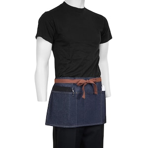 May include: A denim blue waist apron with a brown tie and pockets. The apron is worn over a black t-shirt and black pants. The apron has a brown waistband and a pocket for pens and a notepad.