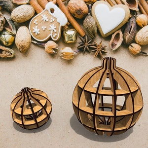 Op de afbeelding: Twee houten kerstballen in de vorm van een bol. De grotere bal is ongeveer 15 cm in diameter en de kleinere bal is ongeveer 7,5 cm in diameter. Beide ballen zijn gemaakt van dun hout en hebben een traliewerkontwerp.