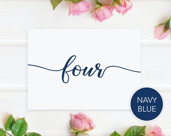 May include: A white card with the word "four" written in navy blue cursive script. The card is surrounded by pink roses and green leaves.