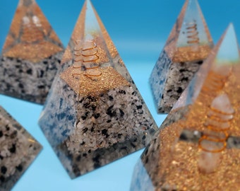 May include: Five clear resin pyramids with gold glitter and copper wire accents. The pyramids are filled with black and white stones.