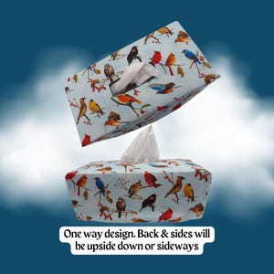 May include: A rectangular tissue box cover featuring a light blue background with a colorful pattern of various birds perched on branches. A white tissue is visible at the top. Text reads: One way design. Back & sides will be upside down or sideways.