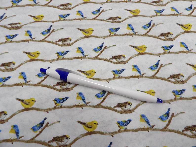 May include: White and blue ballpoint pen on a white fabric patterned with yellow, blue, and brown birds perched on branches. The birds are in various poses, creating a nature-themed design.
