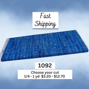May include: A rectangular piece of blue cork fabric featuring a natural, textured pattern with gold-toned flecks throughout. The material is folded and displayed horizontally, showcasing a vibrant, deep blue color palette with organic, linear details.