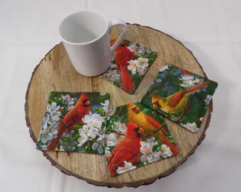 1560 Red cardinals set of four coasters. Various scenes of male and female cardinals among apple blossoms. Mug mats, mug rugs, candle mats.