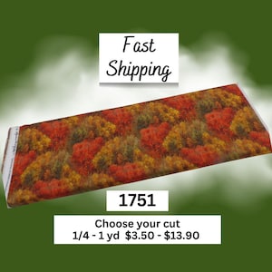 May include: A rectangular piece of fabric featuring a dense, repeating pattern of autumn trees with vibrant red, orange, and yellow foliage. The fabric is displayed at an angle, showcasing the detailed forest landscape print across its surface.