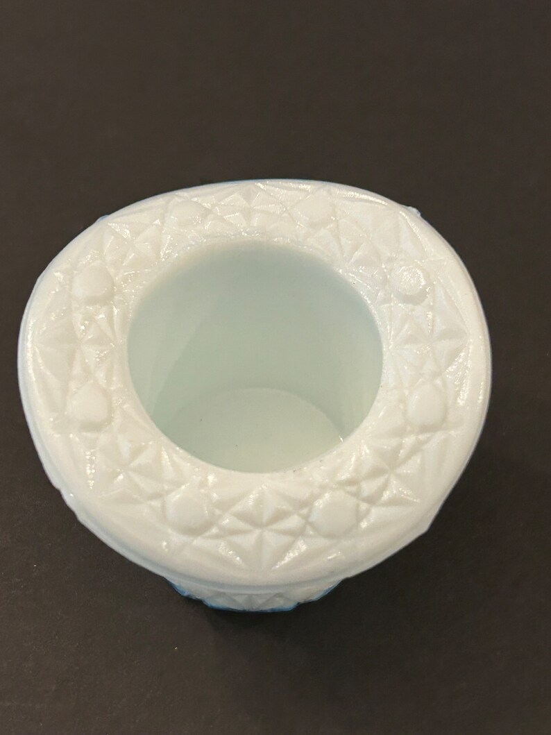 May include: White milk glass hat shaped trinket dish with a raised, geometric design around the rim.