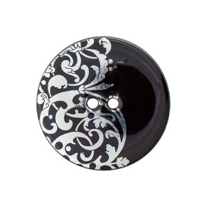 Può includere: Bottone nero con un designo floreale argentato. Il bottone ha due fori.