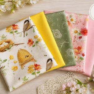 Könnte beinhalten: Ein Set aus fünf Stoffstücken in verschiedenen Farben und Mustern. Ein Stoff zeigt ein Vogel-, Nest- und Bienenwaben-Design. Weitere Stoffe sind einfarbig gelb, grün mit floralem Muster, rosa mit Blumen und einfarbig rosa. Das Set ist mit floralen Akzenten arrangiert.