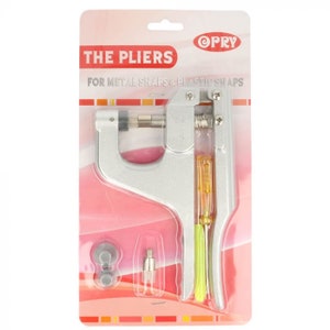Peut inclure: Pince en métal argentée pour fixer les boutons pression en métal et en plastique. La pince a une poignée jaune et est livrée avec deux pièces supplémentaires. L'emballage indique "The Pliers" et "For Metal Snaps & Plastic Snaps".