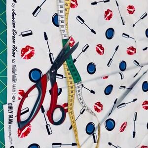 Baumwollstoff mit Kosmetik-Motiven, dekoriert mit Maßband und Stoffschere zur Größenorientierung.