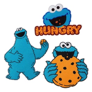 Könnte beinhalten: Drei Cookie Monster-Charakteraufnäher aus der Sesamstraße. Einer ist ein Kopf mit dem Wort "HUNGRY" darüber. Ein weiterer ist ein ganzer Körper, der einen Keks hält. Der dritte ist ein ganzer Körper, der einen Keks hält.