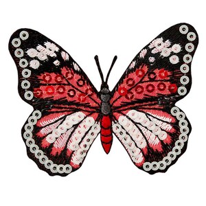 Może przedstawiać: Naszywka z haftowanym motylem w kolorze czerwonym i czarnym z białymi i czerwonymi cekinami.