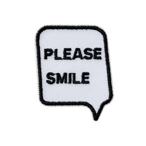 Könnte beinhalten: Weißer Bügel-Patch mit schwarzen Nähten und dem Text "PLEASE SMILE" in Form einer Sprechblase.